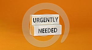 Urgently needed symbol. Concept words Urgently needed on wooden blocks on a beautiful orange table orange background. Business and