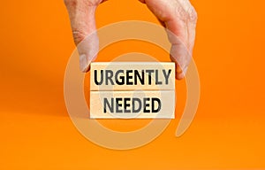 Urgently needed symbol. Concept words Urgently needed on wooden blocks on a beautiful orange table orange background. Businessman