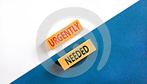 Urgently needed symbol. Concept words Urgently needed on wooden blocks on a beautiful white and blue background. Business and