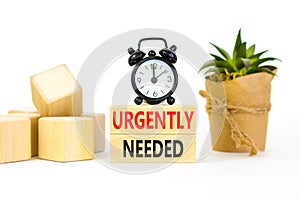 Urgently needed symbol. Concept words Urgently needed on wooden blocks on a beautiful white table white background. Black alarm
