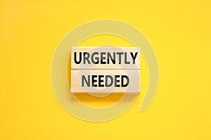 Urgently needed symbol. Concept words Urgently needed on wooden blocks on a beautiful yellow table yellow background. Business and