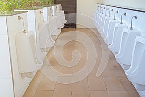 Urinals in building for men only, Close-up row of indoor white ceramic male urinals toilet in public park