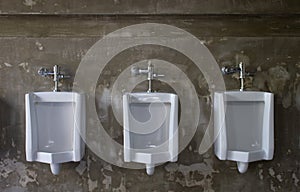 Urinals on concrete wall in public toilet.