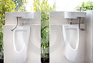 Urinals for men to urinate and hand washing point in the male toilet at park,white urinal with a sink on top of the urinal to photo