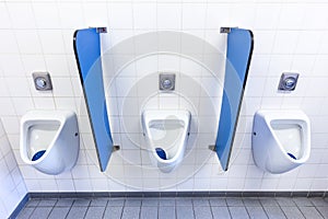 Urinals for men on white wall with blue partitions