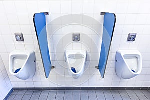 Urinals for men on white wall with blue partitions photo