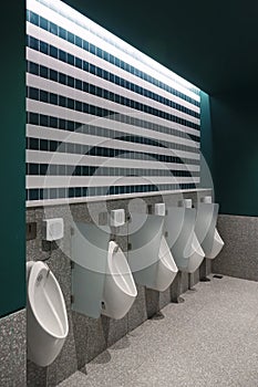 Urinals in a stylish toilet with dark green walls