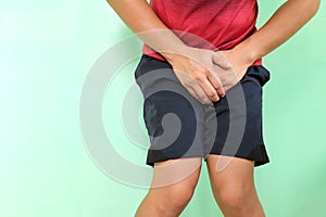 Urinary incontinence, UTI and control urine in male concept. Young asian athlete man grabbing his groin