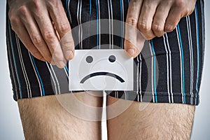 Urinary or prostate problems concept. Young man holds paper with SOS above crotch. photo