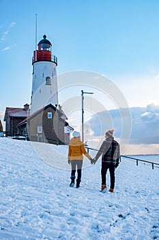Urk Netherlands lighthouse during winter with snow covered coastline, Urk view at the lighthouse snowy landscape winter