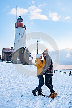 Urk Netherlands lighthouse during winter with snow covered coastline, Urk view at the lighthouse snowy landscape winter