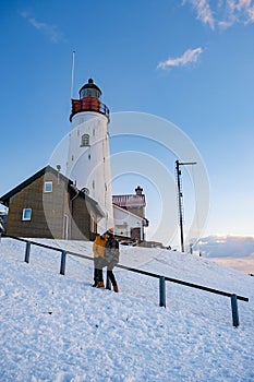 Urk Netherlands lighthouse during winter with snow covered coastline, Urk view at the lighthouse snowy landscape winter