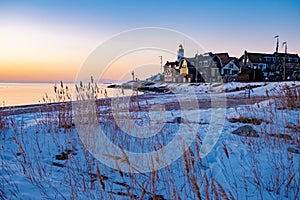 Urk Netherlands lighthouse during winter with snow covered coastline, Urk view at the lighthouse snowy landscape winter