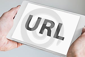 URL text displayed on touch screen of modern tablet. Hands holding white mobile device