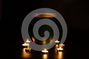 GREEN URNA WITH GOLDEN EDGE surrounded with small burning candles photo