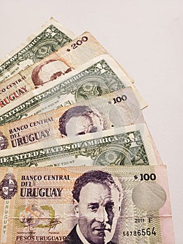 uruguayan banknotes and American one dollar bills on white background