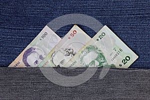 uruguayan banknotes of different denomination between blue denim fabric