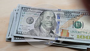 US 100 dollar bills being laid out and counted on a table