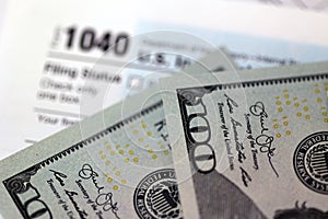 US 1040 individual income tax return form with 100 dollar bills.