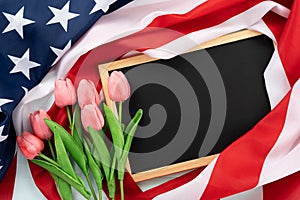 US American flag with blackboard and tulip flower on blue wooden background. For USA Memorial day, Presidents day, Veterans day,