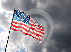 US American flag waving in stormy cloudy sky