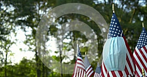 US American flags blowing in the wind with medical face mask hanging off USA flag