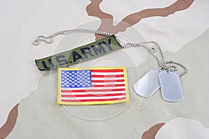 US ARMY branch tape with dog tags and flag patch on desert camouflage uniform