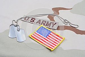 US ARMY branch tape with dog tags and US flag patch on desert camouflage uniform