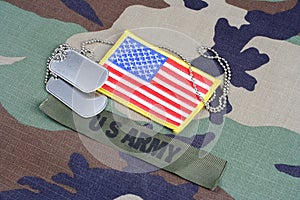 US ARMY branch tape, flag patch and dog tags on woodland camouflage uniform