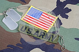 US ARMY branch tape, flag patch and dog tags on woodland camouflage uniform