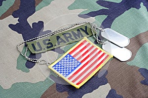 US ARMY branch tape, flag patch and dog tags on woodland camouflage uniform