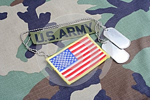 US ARMY branch tape, flag patch and dog tags on woodland camouflage uniform