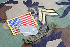 US ARMY Corporal rank patch, branch tape, flag patch and dog tags on woodland camouflage uniform