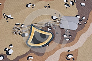 US ARMY Private First Class rank patch and dog tags on desert camouflage uniform