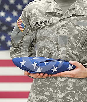 US Army soldier holding folded USA flag before his chest