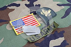 US ARMY Specialist rank patch, branch tape, flag patch and dog tags on woodland camouflage uniform