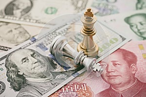 The US and China trade war and currency war concept. Two king chess piece fight on US dollar and Chinese yuan renminbi banknotes