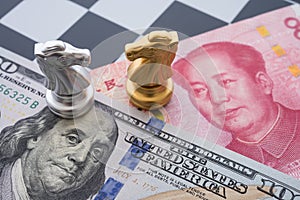 US and China trade war and currency war concept. Two knights chess face to face on chessboard, US dollar and Chinese yuan renminbi