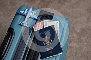 A US citizen passport and American dollars lie next to a model airplane on a travel baggage