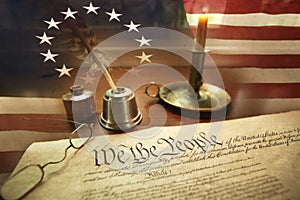 US Constitution with quill pen, glasses, candle, ink and flag