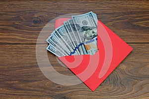 US dollar banknotes in the red envelope on wood table, bonus, reward, benefits concept.