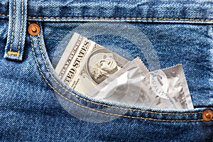 US dollar and condom in front pocket of blue jeans