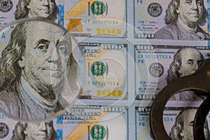 100 US dollars banknotes under magnifying glass of counterfeit money and handcuffs