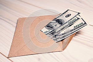 US dollars in an envelope on a wooden table. Income  bonuses or bribes concept