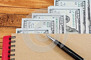 US dollars, notepad and pen on the table