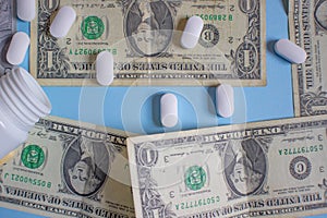 US dollars with pills. White pills spilling from a medical bottle. Concept of health insurance and healthcare