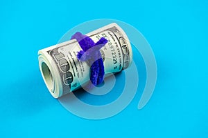 US dollars rolled up and tightened with colored band on light blue background