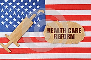 On the US flag there is a cardboard figure of a syringe and a torn cardboard with the inscription - HEALTH CARE REFORM