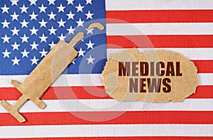 On the US flag there is a cardboard figure of a syringe and a torn cardboard with the inscription - MEDICAL NEWS