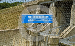 US government no trespassing sign posted om wired fence limiting access to a dam photo